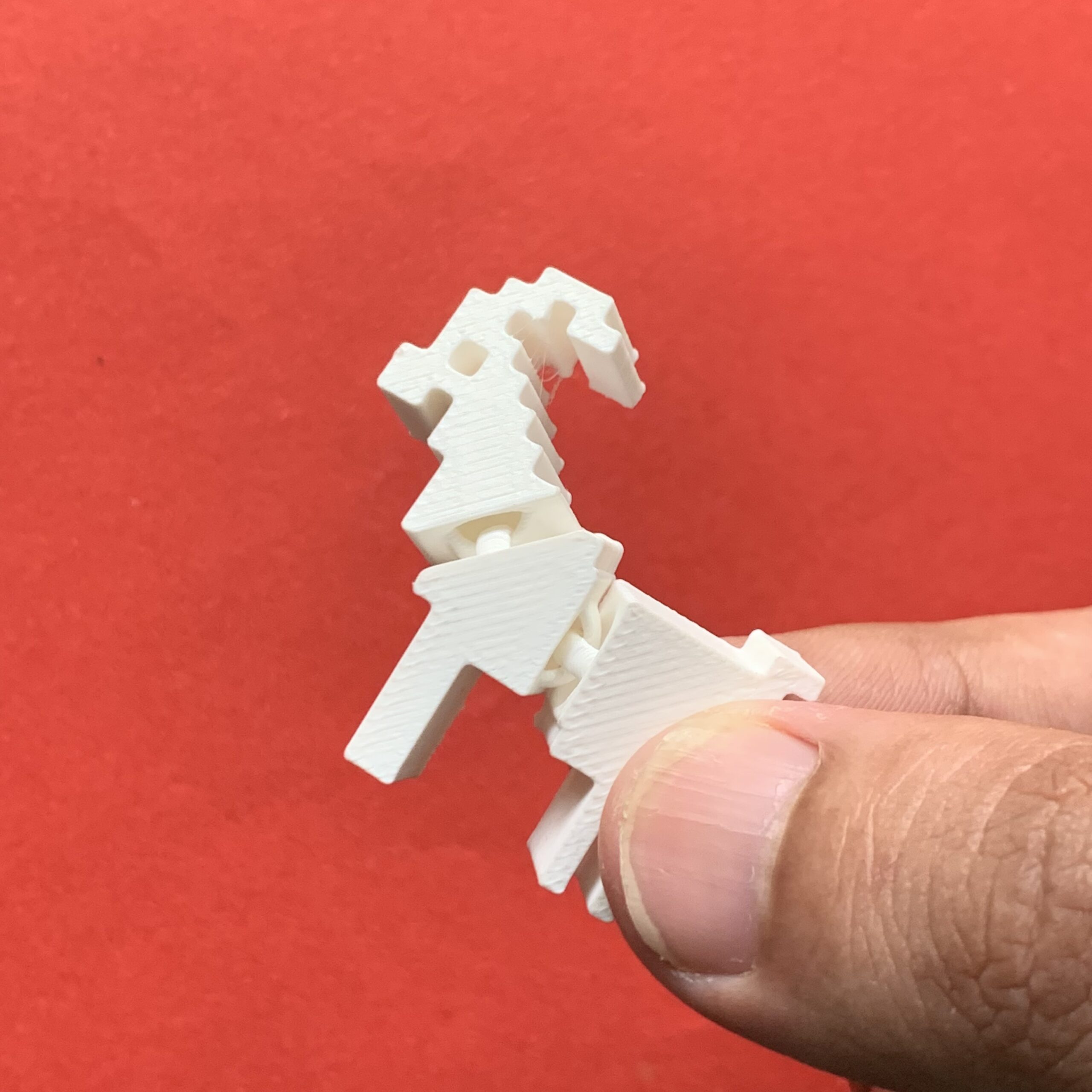 Holding 3d Printed Pixel Goat Flexi Keychain White