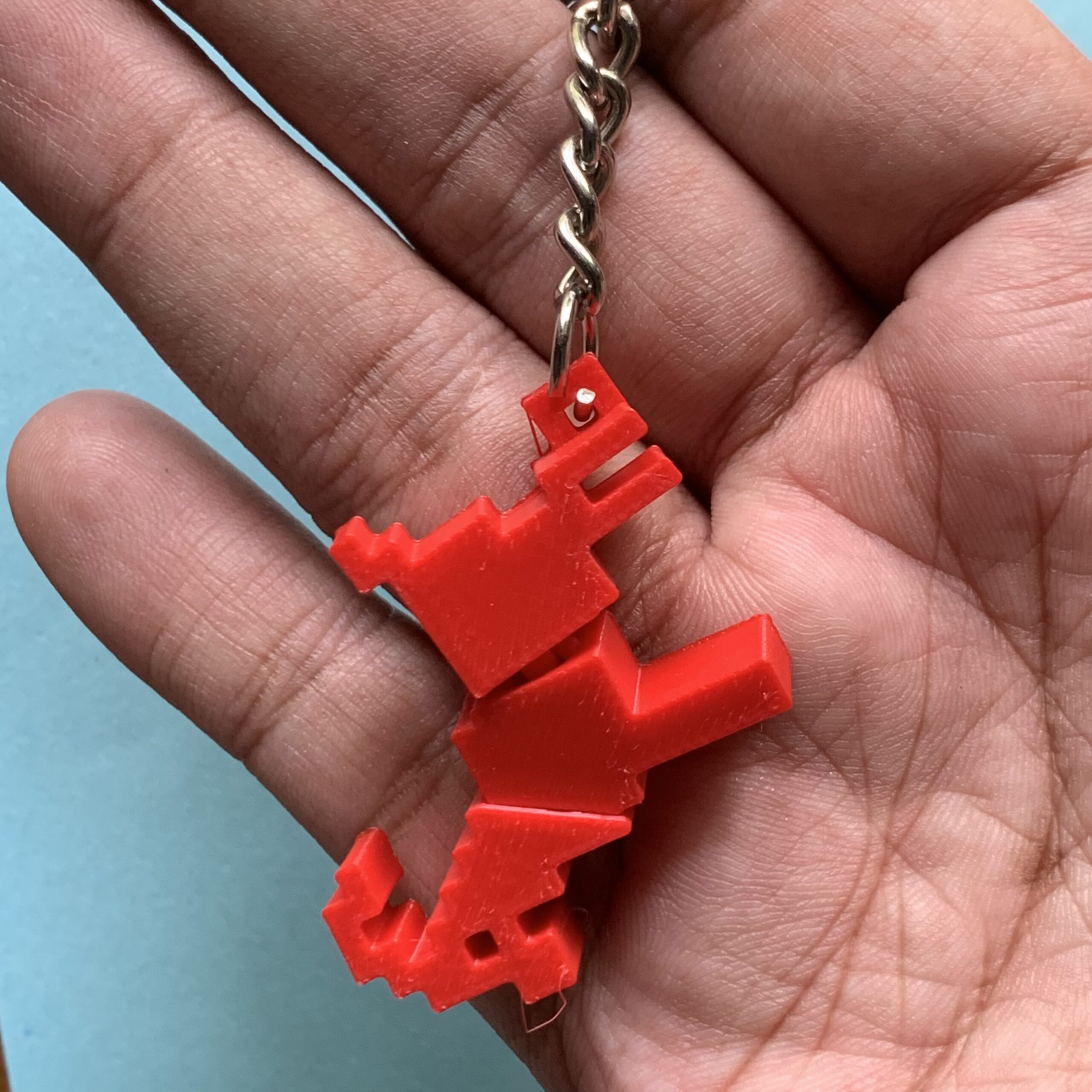 Showing 3d Printed Pixel Goat Flexi Keychain Red on Hand